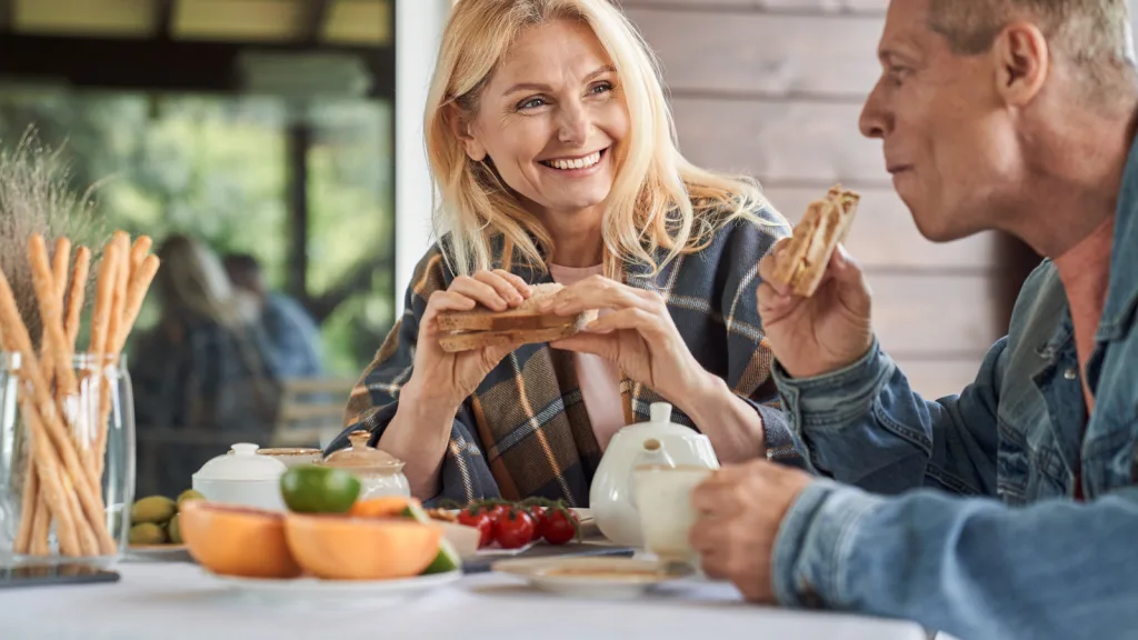 Texas- Older couple sitting down eating at an outdoor patio restaurant. New pet-friendly apartment homes for rent with private fenced backyards in Texas with pool, pickleball, dog park, gym, clubhouse and gated community. *No breed or weight restrictions. Yardly